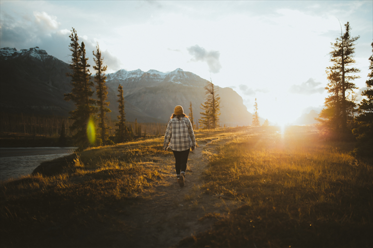Person geht bei Sonnenuntergang einen Weg durch eine Berglandschaft